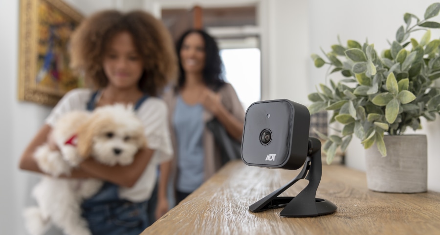 Up close shot of ADT camera on a table with family in the background.